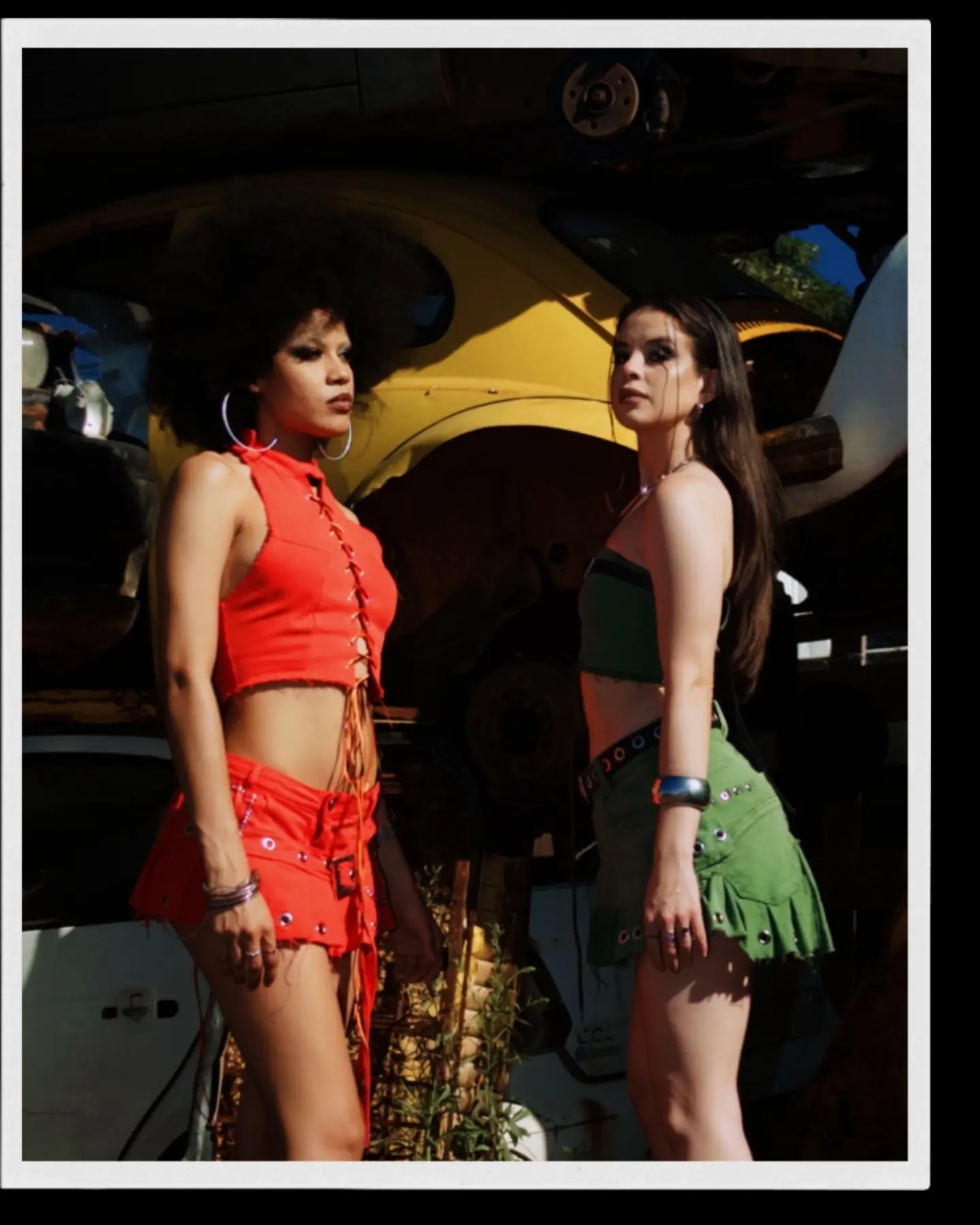 As duas modelos com os looks vermelho e verde em moldura fotográfica.